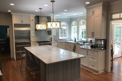 Inspiration for a mid-sized timeless l-shaped medium tone wood floor and brown floor eat-in kitchen remodel in Atlanta with shaker cabinets, white cabinets, granite countertops, gray backsplash, mosaic tile backsplash, stainless steel appliances, an island and white countertops