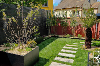 Small modern backyard garden in Paris with a wood fence.