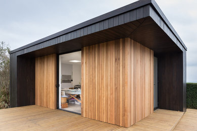 Inspiration for a small contemporary one-storey exterior in Channel Islands with wood siding and a flat roof.