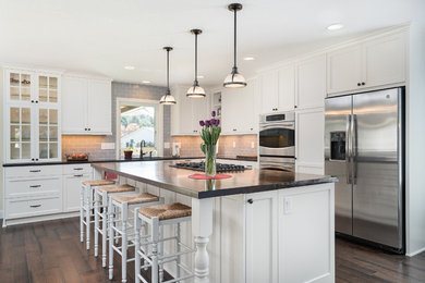 Inspiration for a mid-sized cottage l-shaped dark wood floor eat-in kitchen remodel in Portland with an integrated sink, flat-panel cabinets, white cabinets, wood countertops, gray backsplash, subway tile backsplash, stainless steel appliances and an island