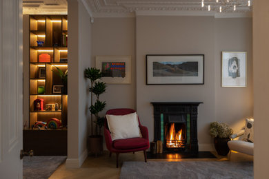 Modelo de salón para visitas abierto actual de tamaño medio con paredes beige, suelo de madera en tonos medios y marco de chimenea de yeso
