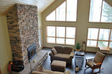 Inspiration for a transitional open concept living room in Other with beige walls, medium hardwood floors, a wood stove and a stone fireplace surround.