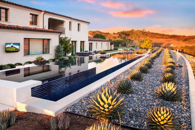 Large backyard stone and rectangular infinity pool landscaping photo in Orange County