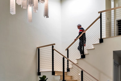 Foto de escalera en U clásica renovada de tamaño medio con escalones de madera, contrahuellas de madera y barandilla de cable