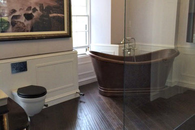 Ejemplo de cuarto de baño principal clásico grande con lavabo encastrado, encimera de vidrio, bañera exenta, ducha abierta, sanitario de pared, baldosas y/o azulejos negros, baldosas y/o azulejos en mosaico, paredes grises y suelo de madera en tonos medios