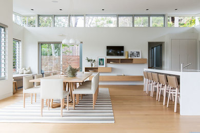 Photo of a beach style dining room in Sydney with white walls and light hardwood floors.