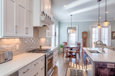 Mid-sized transitional l-shaped medium tone wood floor and brown floor open concept kitchen photo in Other with an undermount sink, recessed-panel cabinets, white cabinets, quartzite countertops, white backsplash, glass tile backsplash, stainless steel appliances, an island and white countertops