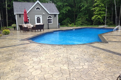 Example of a mid-sized island style backyard stamped concrete and l-shaped natural pool design in Portland Maine