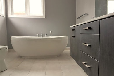 Inspiration for a large transitional master gray tile and porcelain tile porcelain tile and gray floor bathroom remodel in Toronto with flat-panel cabinets, dark wood cabinets, a one-piece toilet, gray walls, an undermount sink and quartz countertops