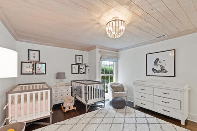 Imagen de habitación de bebé neutra bohemia de tamaño medio con paredes blancas, suelo de madera en tonos medios, suelo marrón y madera