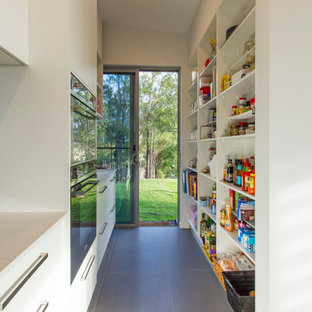 Inredning av ett modernt litet kök, med en undermonterad diskho, bänkskiva i kvarts, grått stänkskydd, stänkskydd i porslinskakel, rostfria vitvaror, klinkergolv i porslin och en köksö