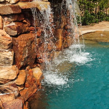 Lagoon style swimming pool with waterfall grotto with spa inside.