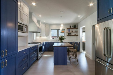 Large transitional l-shaped bamboo floor enclosed kitchen photo in Other with an undermount sink, shaker cabinets, blue cabinets, solid surface countertops, white backsplash, stainless steel appliances and an island