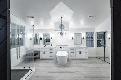 Example of a large minimalist master white tile and ceramic tile laminate floor, gray floor, double-sink and vaulted ceiling bathroom design in Las Vegas with shaker cabinets, white cabinets, a two-piece toilet, white walls, an undermount sink, quartzite countertops, a hinged shower door, white countertops and a built-in vanity