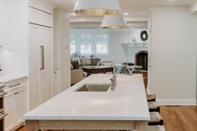 Idée de décoration pour une cuisine design avec des portes de placard blanches, îlot et un plan de travail blanc.
