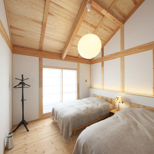 Foto di una camera da letto etnica con pareti bianche, pavimento in legno massello medio e pavimento marrone