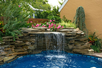 This is an example of a large contemporary backyard custom-shaped lap pool in New York with a hot tub and natural stone pavers.