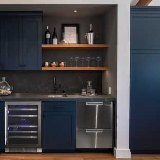 Immagine di un grande angolo bar con lavandino chic con lavello da incasso, ante con bugna sagomata, ante blu, top in granito, paraspruzzi grigio, paraspruzzi in granito, parquet chiaro, pavimento marrone e top grigio