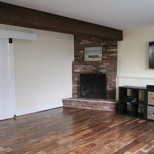 ニューヨークの中サイズのトラディショナルスタイルのおしゃれな地下室 (半地下 (窓あり) 、ベージュの壁、無垢フローリング、標準型暖炉、レンガの暖炉まわり) の写真