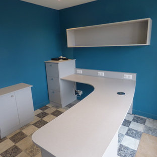 Foto på ett stort funkis arbetsrum, med ett bibliotek, blå väggar, laminatgolv, ett fristående skrivbord och flerfärgat golv