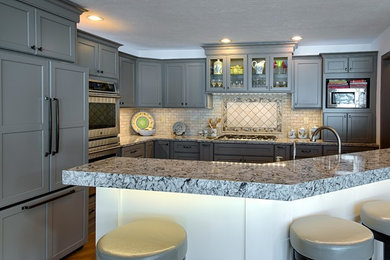 Enclosed kitchen - mid-sized transitional u-shaped medium tone wood floor and gray floor enclosed kitchen idea in Other with an undermount sink, shaker cabinets, gray cabinets, quartz countertops, beige backsplash, stone tile backsplash, stainless steel appliances and a peninsula
