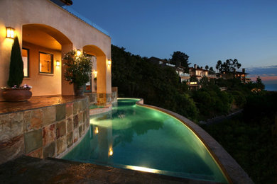 Inspiration for a large mediterranean stone and custom-shaped infinity pool remodel in Orange County