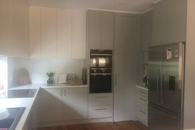 Photo of a small contemporary u-shaped separate kitchen in Melbourne with a double-bowl sink, grey cabinets, quartz benchtops, white splashback, stone slab splashback, stainless steel appliances, dark hardwood floors, with island and white benchtop.