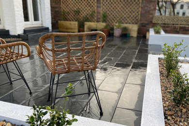 Ejemplo de patio actual de tamaño medio en patio trasero con adoquines de piedra natural