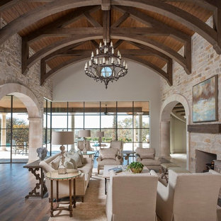 Geräumiges, Offenes Mediterranes Wohnzimmer mit beiger Wandfarbe, hellem Holzboden, Kamin, Kaminsims aus Stein und Wand-TV in Dallas