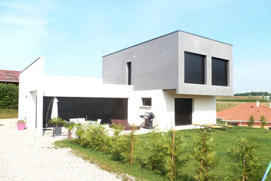 Large contemporary two-storey concrete grey house exterior in Lyon with a flat roof.