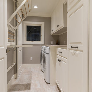 オースティンの中サイズのトラディショナルスタイルのおしゃれな家事室 (レイズドパネル扉のキャビネット、白いキャビネット、御影石カウンター、ベージュの壁、磁器タイルの床、左右配置の洗濯機・乾燥機) の写真