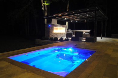 Contemporary backyard pool in Indianapolis with natural stone pavers.