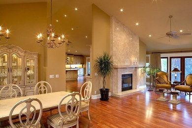 Inspiration for a large timeless formal and open concept medium tone wood floor and brown floor living room remodel in Calgary with beige walls, a standard fireplace, a plaster fireplace and a wall-mounted tv