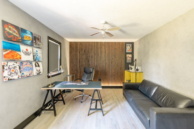 Diseño de despacho actual de tamaño medio con paredes grises, suelo de madera clara, escritorio independiente, suelo gris y madera