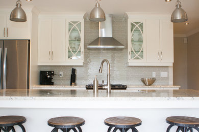 Mid-sized transitional l-shaped linoleum floor eat-in kitchen photo in Montreal with an undermount sink, shaker cabinets, white cabinets, granite countertops, beige backsplash, glass tile backsplash, an island and stainless steel appliances
