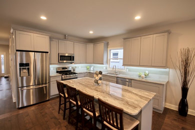 Kitchen - modern brown floor kitchen idea in New York with a double-bowl sink, gray cabinets, granite countertops, blue backsplash, stainless steel appliances, shaker cabinets and an island