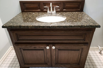 Bathroom - mid-sized traditional ceramic tile bathroom idea in Other with raised-panel cabinets, dark wood cabinets and granite countertops