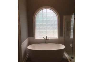 Example of a mid-sized trendy master white tile and ceramic tile vinyl floor, gray floor, double-sink, vaulted ceiling and wainscoting bathroom design in Wilmington with raised-panel cabinets, white cabinets, a one-piece toilet, gray walls, an integrated sink, granite countertops, a hinged shower door, gray countertops, a niche and a freestanding vanity
