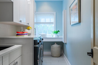 Example of a mid-sized transitional l-shaped ceramic tile and beige floor dedicated laundry room design in New Orleans with an undermount sink, flat-panel cabinets, white cabinets, a side-by-side washer/dryer, white countertops and blue walls