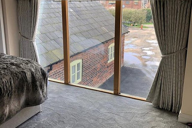This is an example of a medium sized modern guest bedroom in Cheshire with white walls, carpet and grey floors.
