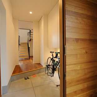 他の地域の中サイズの片開きドアモダンスタイルのおしゃれな玄関ホール (コンクリートの床、グレーの床、白い壁、金属製ドア) の写真