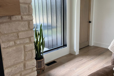 Entryway - mid-sized modern vinyl floor, multicolored floor, vaulted ceiling and wall paneling entryway idea in Los Angeles with white walls and a light wood front door