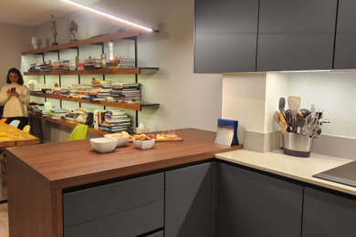 This is an example of a medium sized contemporary enclosed kitchen in Buckinghamshire with flat-panel cabinets, blue cabinets, quartz worktops, a breakfast bar and grey worktops.