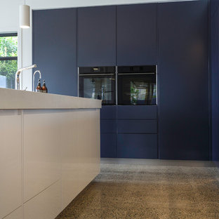 Large contemporary kitchen pantry ideas - Inspiration for a large contemporary l-shaped concrete floor and multicolored floor kitchen pantry remodel in Brisbane with a double-bowl sink, flat-panel cabinets, light wood cabinets, quartz countertops, mirror backsplash, black appliances, an island and white countertops