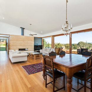 Inspiration for a large contemporary dining room in Central Coast with white walls, light hardwood floors, a standard fireplace, a stone fireplace surround and brown floor.