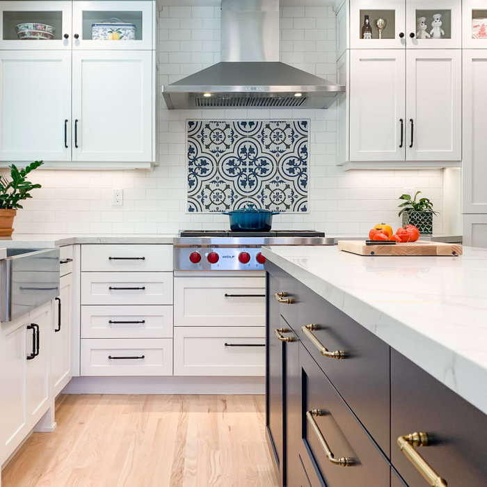 white and blue custom kitchen with a decorative backsplash and gold and black hardware