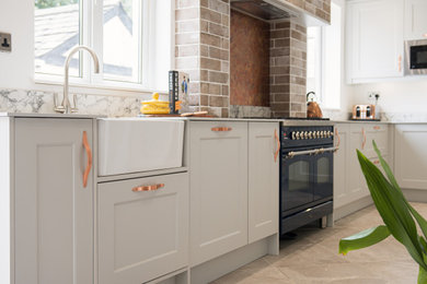 Inspiration for a medium sized traditional grey and white l-shaped enclosed kitchen in Cardiff with a belfast sink, shaker cabinets, grey cabinets, marble worktops, metallic splashback, metal splashback, stainless steel appliances, porcelain flooring, no island, grey floors, white worktops and a chimney breast.