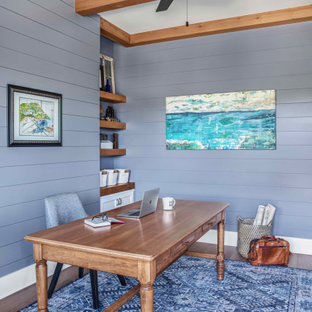 Mittelgroßes Maritimes Arbeitszimmer ohne Kamin mit Arbeitsplatz, blauer Wandfarbe, braunem Holzboden, freistehendem Schreibtisch, braunem Boden, freigelegten Dachbalken und Holzdielenwänden in Austin
