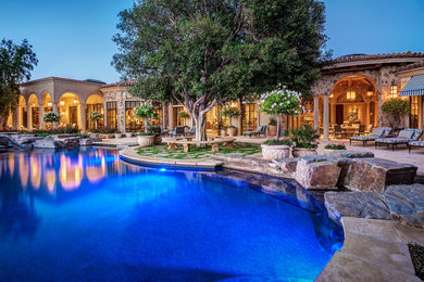 Example of a large tuscan backyard stone and custom-shaped natural pool design in Other