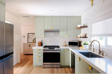 サンフランシスコにあるトランジショナルスタイルのおしゃれなキッチン (緑のキャビネット、白いキッチンパネル、シルバーの調理設備、白いキッチンカウンター) の写真